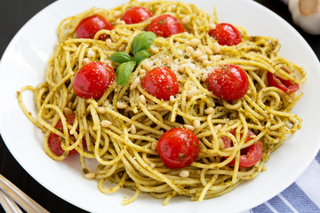 Homemade Pesto Pasta with Tomatoes and Pine Nuts on a black background, low angle view.