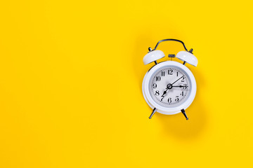 White alarm clock on yellow background