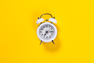 White alarm clock on yellow background