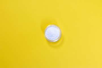 Bowl of baking soda on yellow background. Top view.