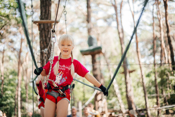 Kleines Mädchen klettert Seile im Abenteuerpark im Freien. 