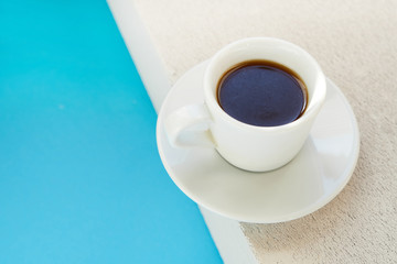 White cup of strong coffee standing on a stone background Copy space