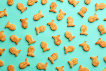 Delicious goldfish crackers on turquoise background, flat lay