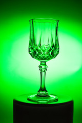 Wineglass on the light background. Fine cristal glassware concept. Vertical, toned in green