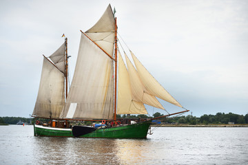 An elegant two-masted gaff schooner (tall ship) sailing near the lighthouse, close-up. Riga bay, Ba;tic sea, Latvia. History, transportation, sport, recreation, cruise, regatta. Concept image