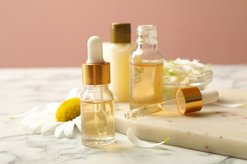 Chamomile and cosmetic products on white marble table