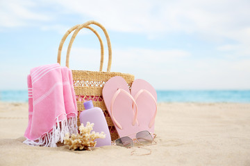 Different stylish beach objects and coral on sand near sea. Space for text