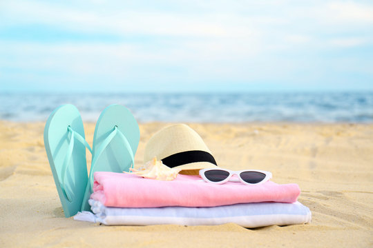 Different stylish beach objects and seashell on sand near sea
