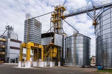Modern Granary elevator. Silver silos on agro-processing and manufacturing plant for processing drying cleaning and storage of agricultural products, flour, cereals and grain.