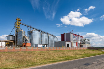 Fototapeta na wymiar Modern Granary elevator. Silver silos on agro-processing and manufacturing plant for processing drying cleaning and storage of agricultural products, flour, cereals and grain.