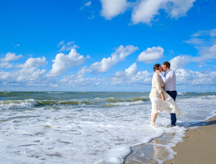 Happy bride and groom hugging on beach