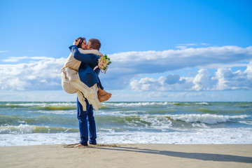 Happy bride and groom hugging on beach