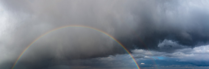Rainbow and storm clouds at sunrise