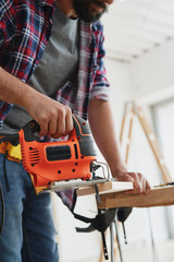 Close up of carpenter sawing wood with an electric jigsaw