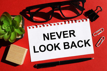 NEVER LOOK BACK concept. TEXT is written on white paper on a red background near the stationery.