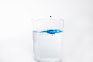 Blue Water Drop Falling Down in a Glass with Water.
