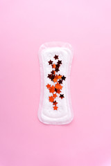 Creative health concept photo of hygiene protection woman menstrual period pad with stars confetti on pink background.