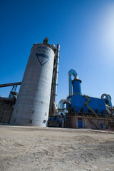 Mynaral, Kazakhstan: Jambyl Cement plant. Factory buildings and silos with bright sun. Wide-angle view.