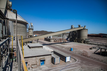 Mynaral, Kazakhstan: Jambyl Cement plant. Industrial buildings and mixing silos. Panorama view. Clear blue sky.