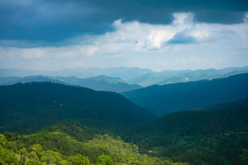 Obraz premium A beautiful and soothing landscape of mountains covered in clouds and green trees during winters.