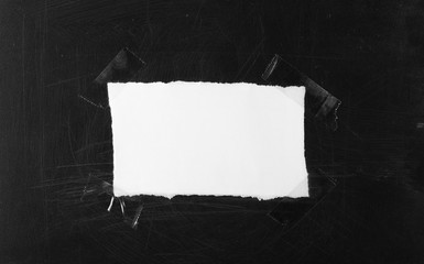 White blank paper scrap with transparent tape on black chalkboard, blackboard background and texture