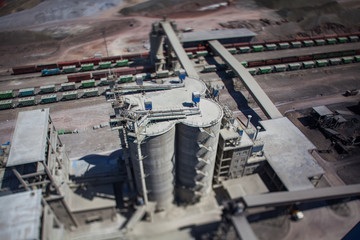 Mynaral/Kazakhstan: Modern cement plant in desert. Hopper cars on railroad terminal. Railway carriages on track. Cement silos on foreground.