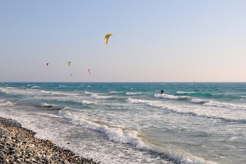 Kitesurfers on a windy day with foamy waves crashing the Kourion beach near Limassol, Cyprus