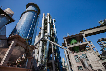 Modern Jambyl Cement plant mixing tower, silo, hoppers, tubes and industrial building on clear blue sky. Wide-angle view. Mynaral, Kazakhstan.