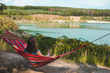 Obraz na płótnie Canvas woman laying on hammock enjoying the view of summer lake