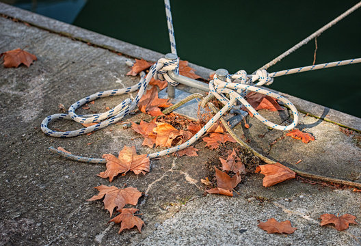 Mooring rope with a knotted end tied around a cleat in autumn