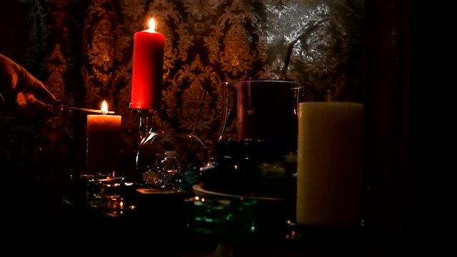 The fortune teller occult Lights the candles on the table. A mystical ritual in the clairvoyant's room.