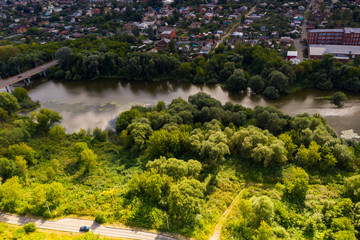 a panoramic view from a drone of a dark river and green trees around in summer