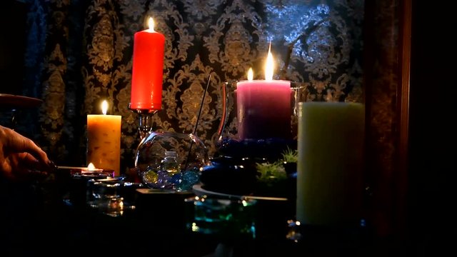 Occult lights the candles on the table. A mystical ritual in the clairvoyant's room.
