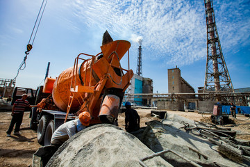 Old phosphate fertilizer plant in modernization. Mobile crane, workers, orange mixer truck, cement...
