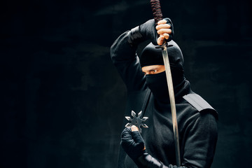 Ninja samurai warrior fighter with a sword and shuriken over black background