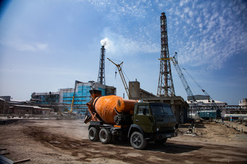 Orange concrete mixer truck, concrete constructions, yellow mobile cranes, blue industrial...
