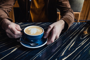Fototapeta na wymiar Close-up of man hand having a cup of cappuccino