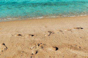 footprints on the beach with soft azure waves
