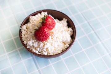 Healthy homemade breakfast. Cottage cheese with strawberries. Proper nutrition, diet. Clay plate with cottage cheese on the background of a turquoise tablecloth