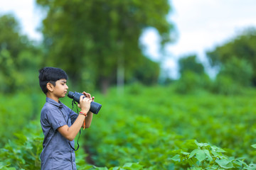 Fototapeta premium little Indian boy enjoys in nature with binoculars