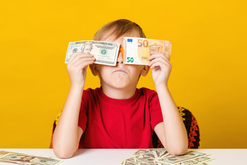 Saving money for future education. Financial literacy of children. Clever child counting money.