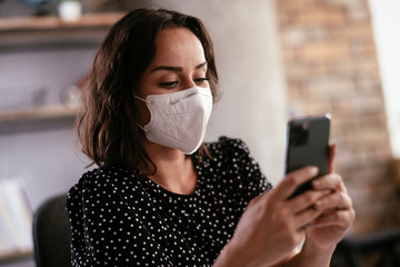 Beautiful businesswoman with medical mask working in office. Young businesswoman uing the phone..