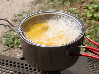 アウトドアでパスタの麺を湯がくシーン

