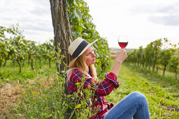 Frau als Winzer schaut prüfend auf Glas Rotwein