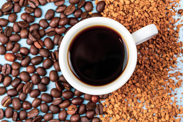 Coffee beans half with instant coffee, in the middle a cup of coffee on a blue background
