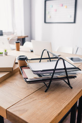 Selective focus of document tray near coffee to go on table in white office