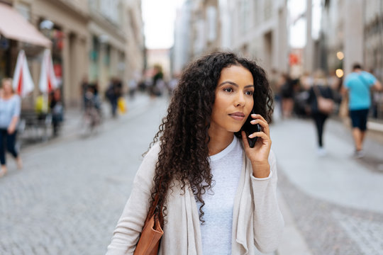 Curly brunette talking by the phone in the street