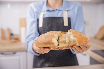 Baker hands break hot fresh round wheat bread into two halves, crunch and crumbs