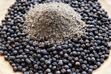 Black pepper powder pile on top of black peppercorns .photo 
