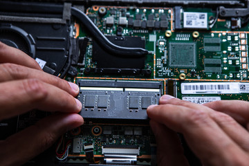 Close-up on the RAM memory that the hands of the service technician insert into the slot on the...